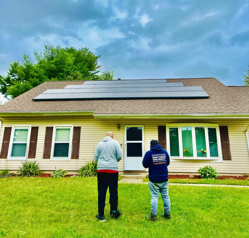 Sunnymac workers stand outside home with solar panels on roof